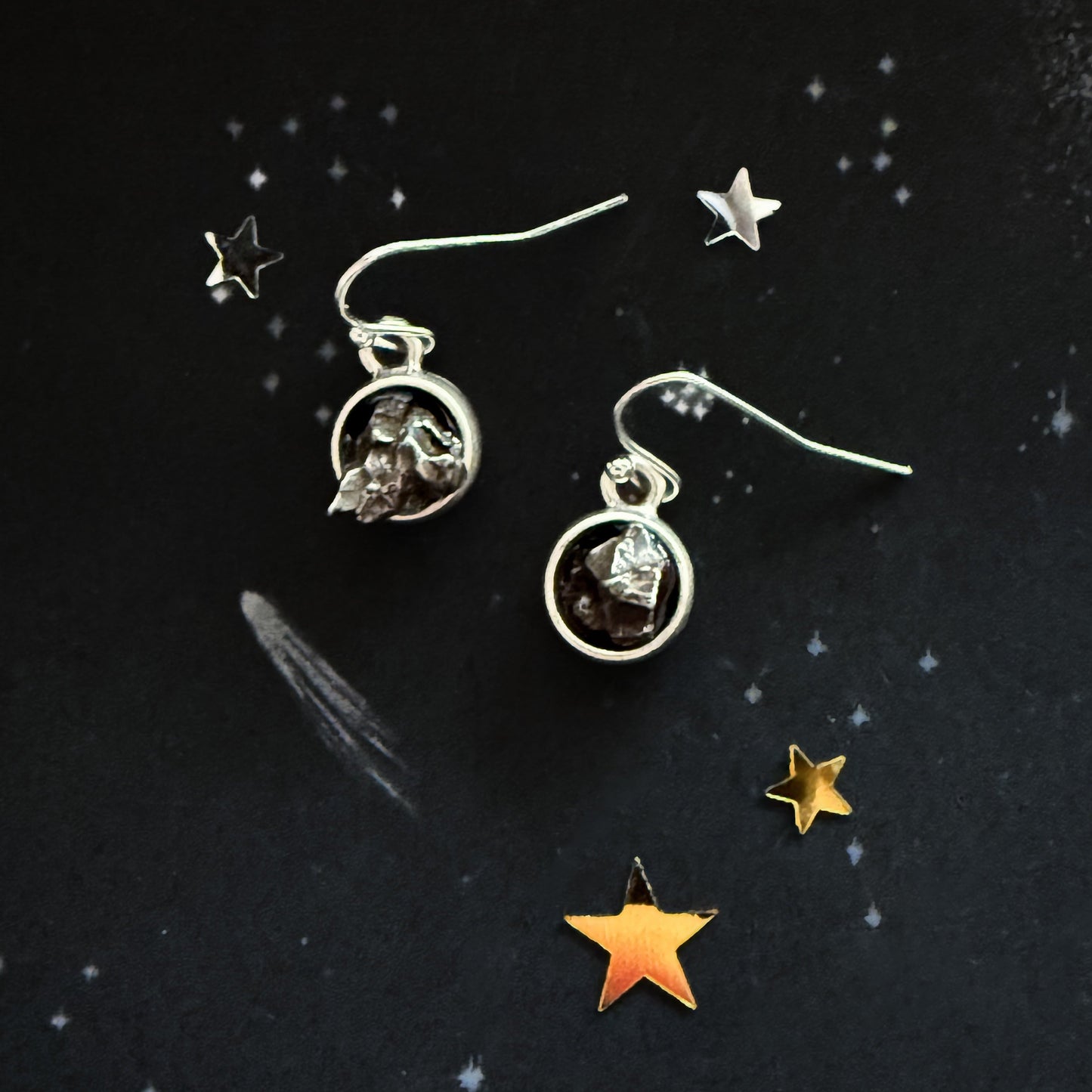Silver earrings with gemstones on a dark background with star decorations