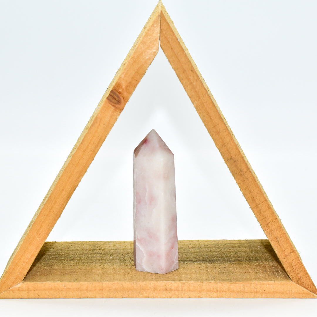 Pink crystal on a wooden triangle stand against a white background