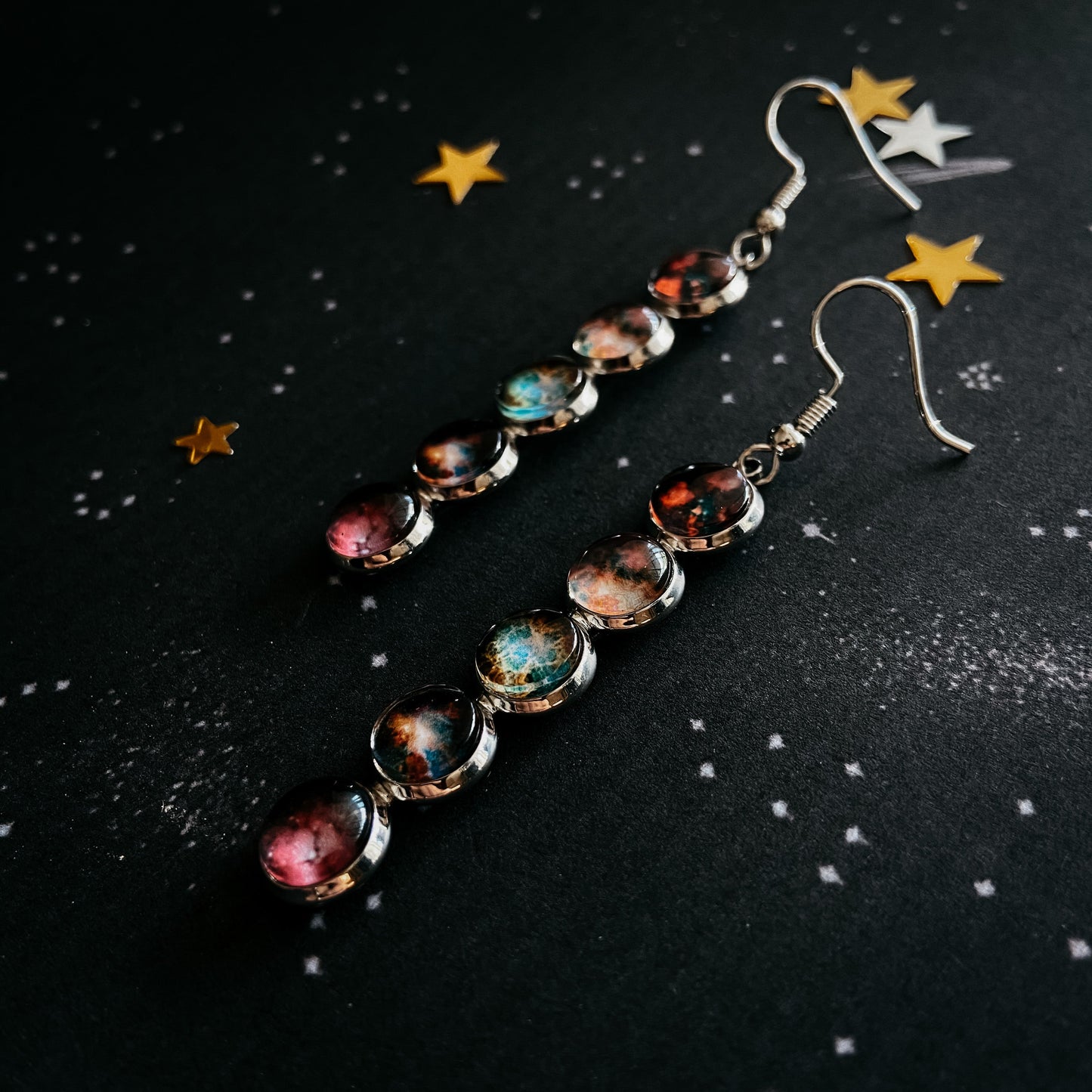 Pair of earrings with colorful beads on a black background with star decorations