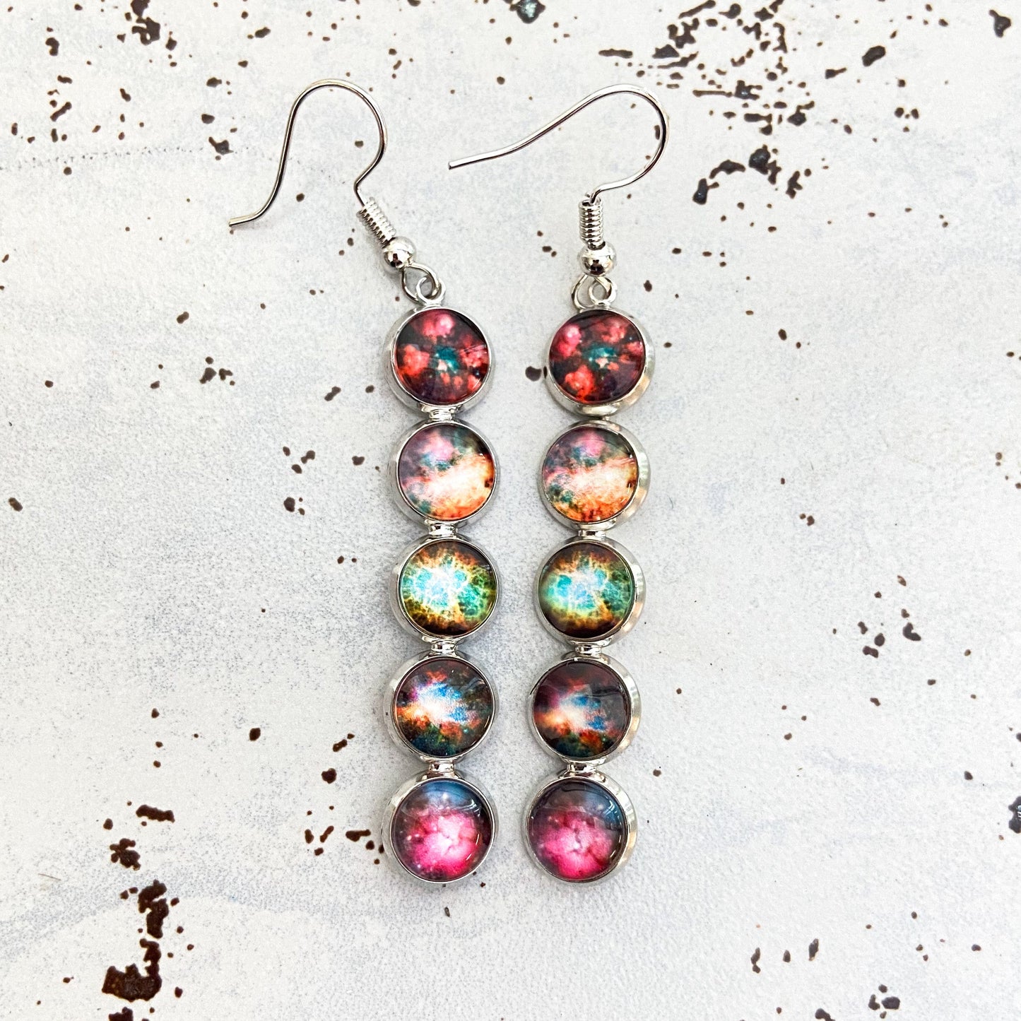 Multicolored round earrings on a textured white surface