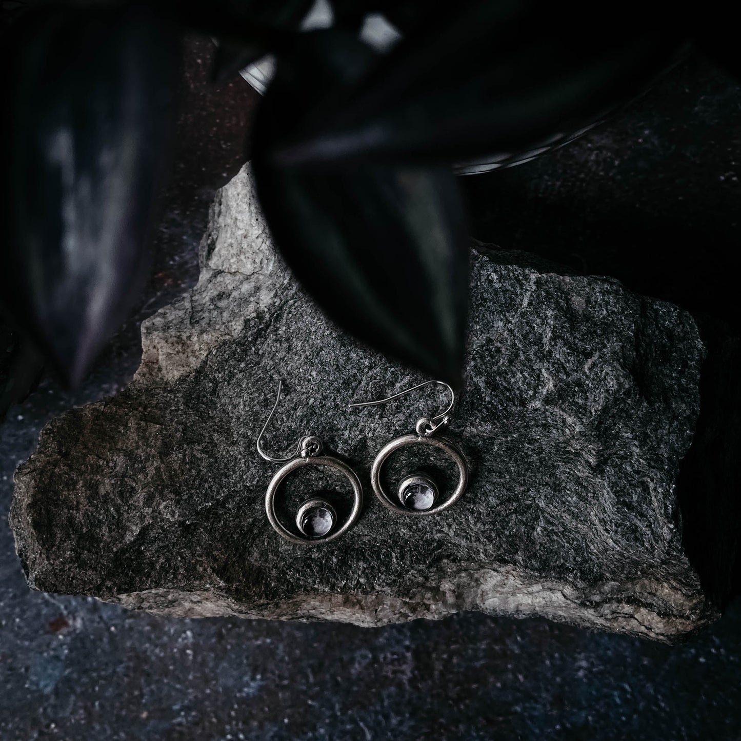 Silver earrings on a dark stone surface
