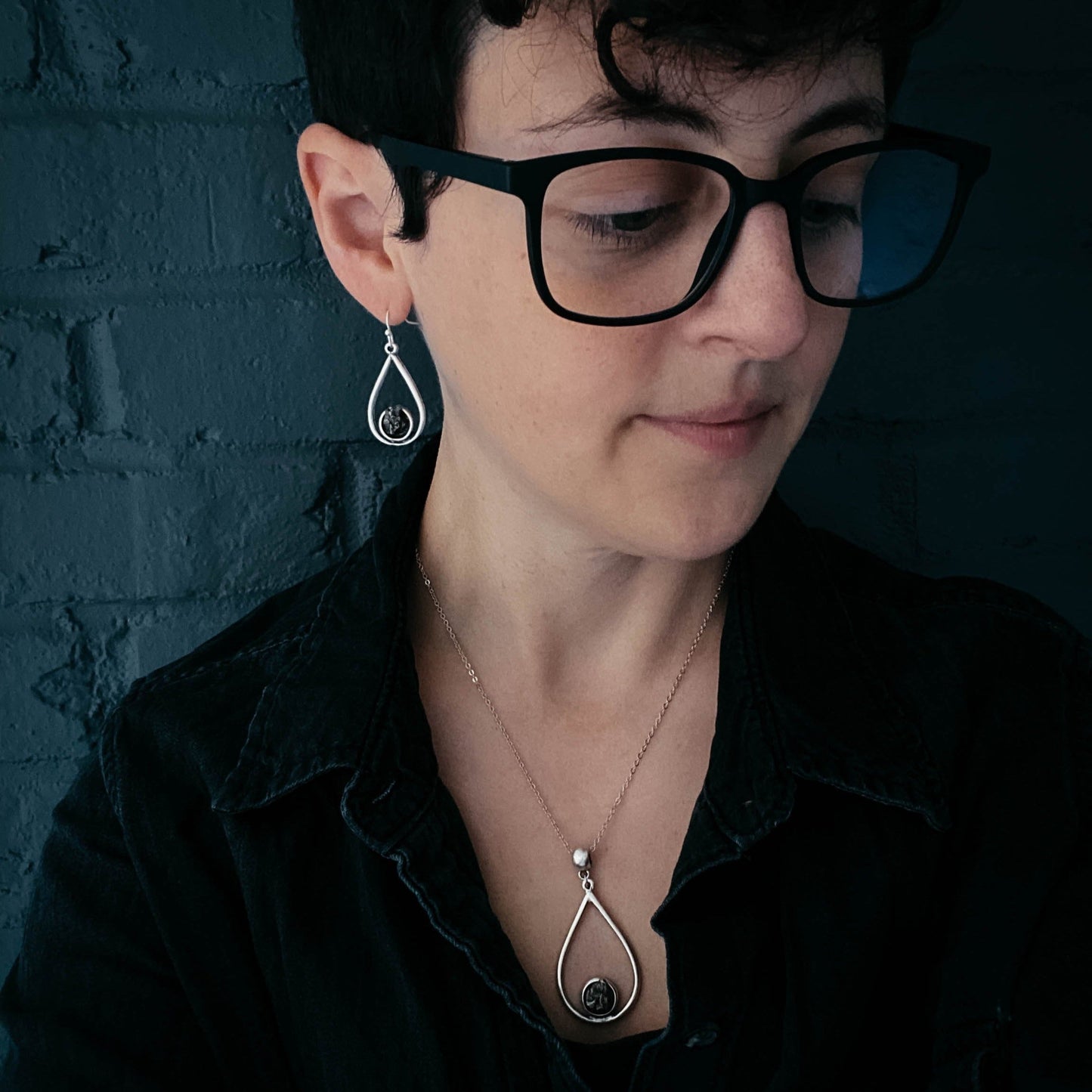 Person wearing black glasses with a dark background