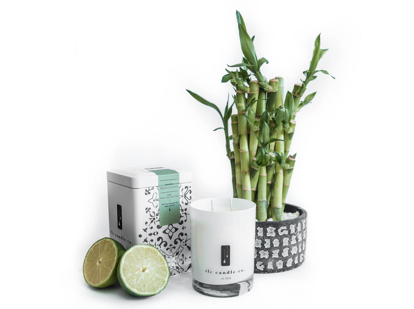 Bamboo plant, candle, and limes on a white background