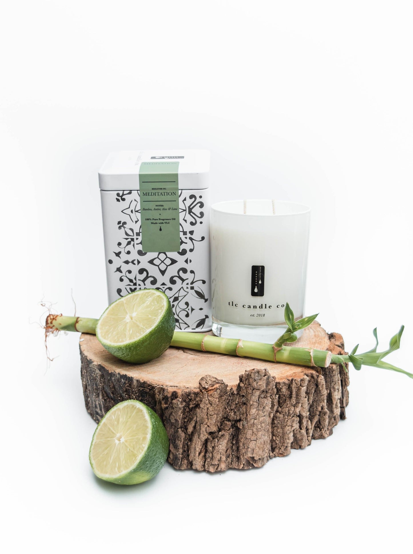 Candle, soap, and limes on a wooden block with a white background
