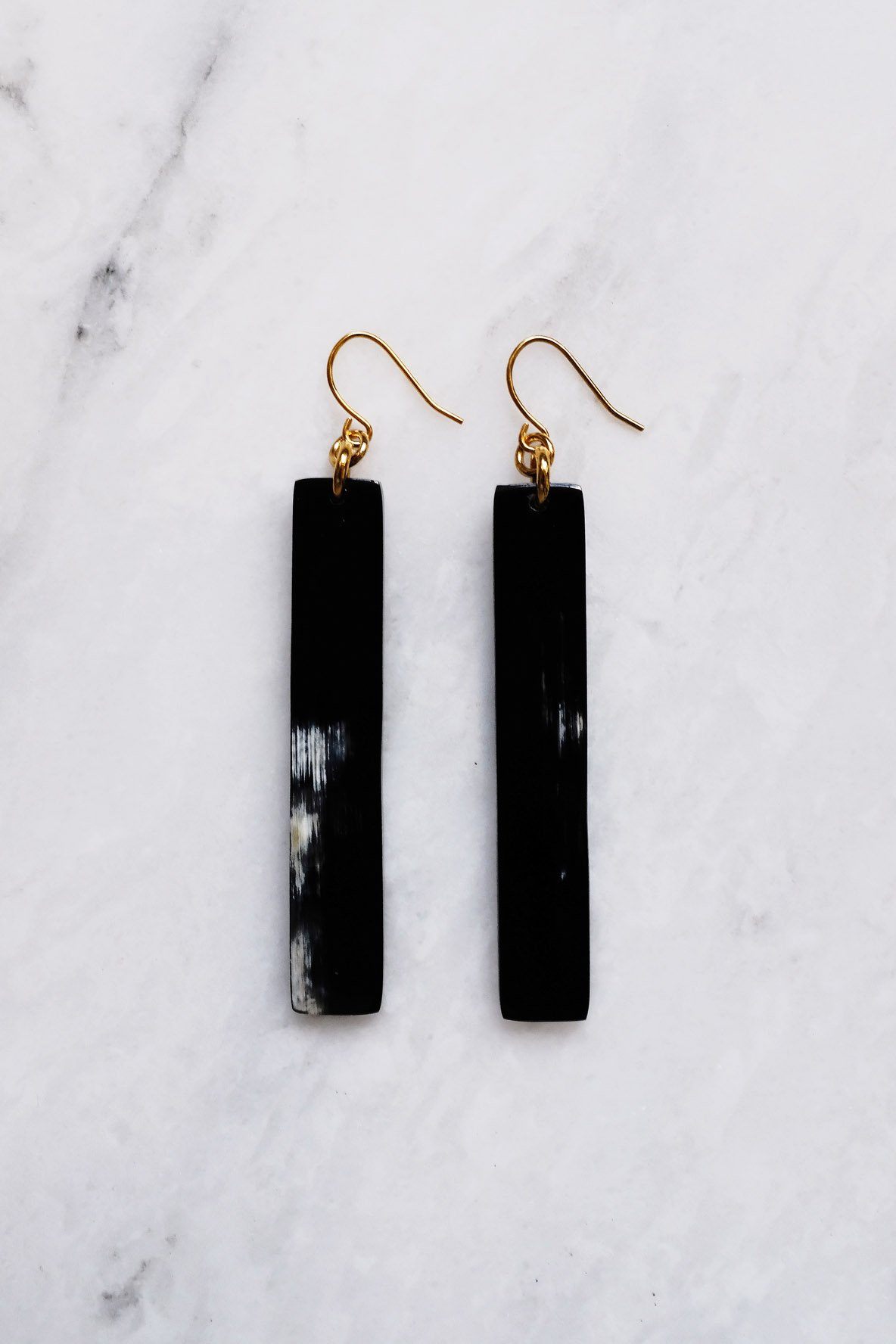 Black bar earrings on a marble surface