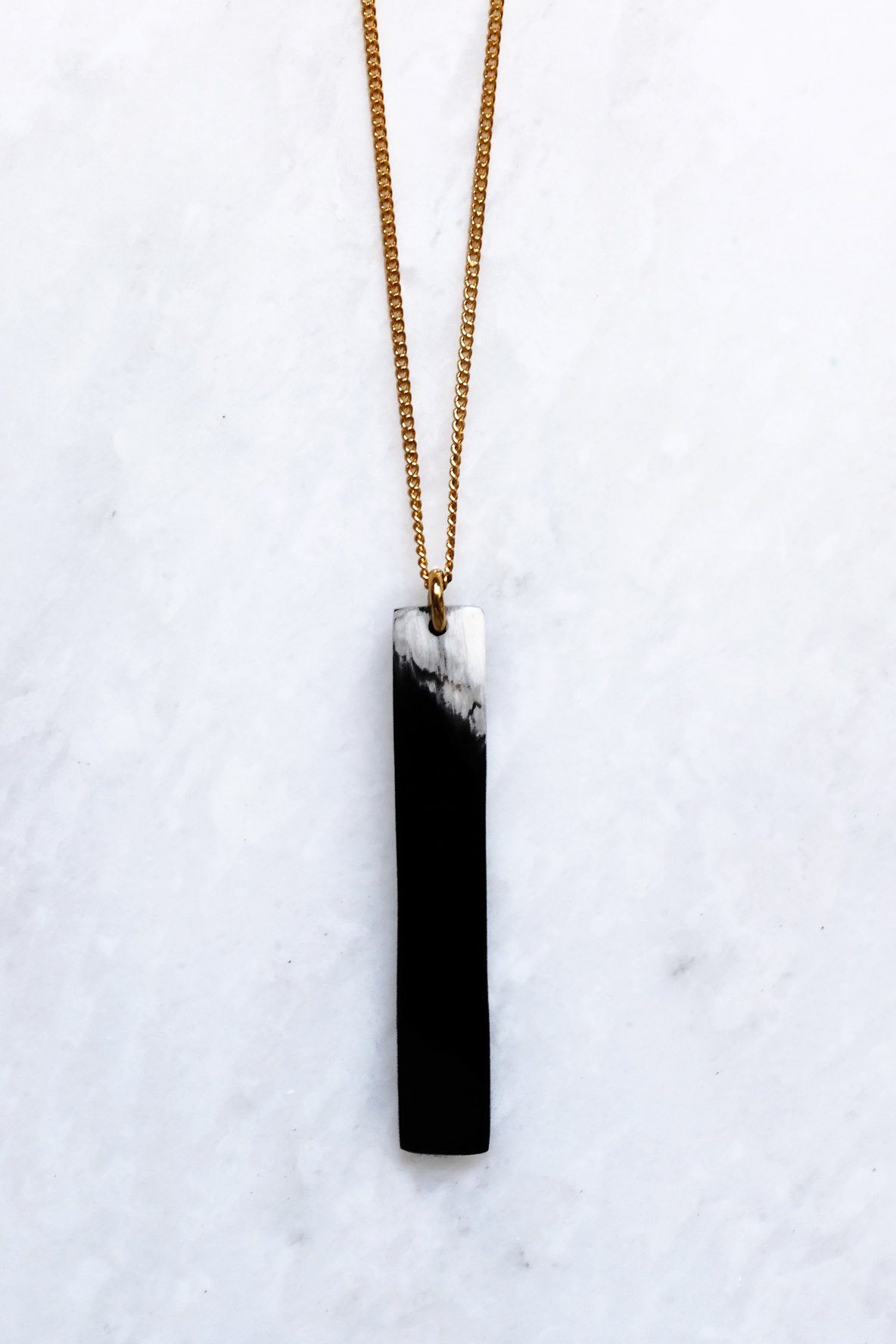 Necklace with a black and white pendant on a marble surface