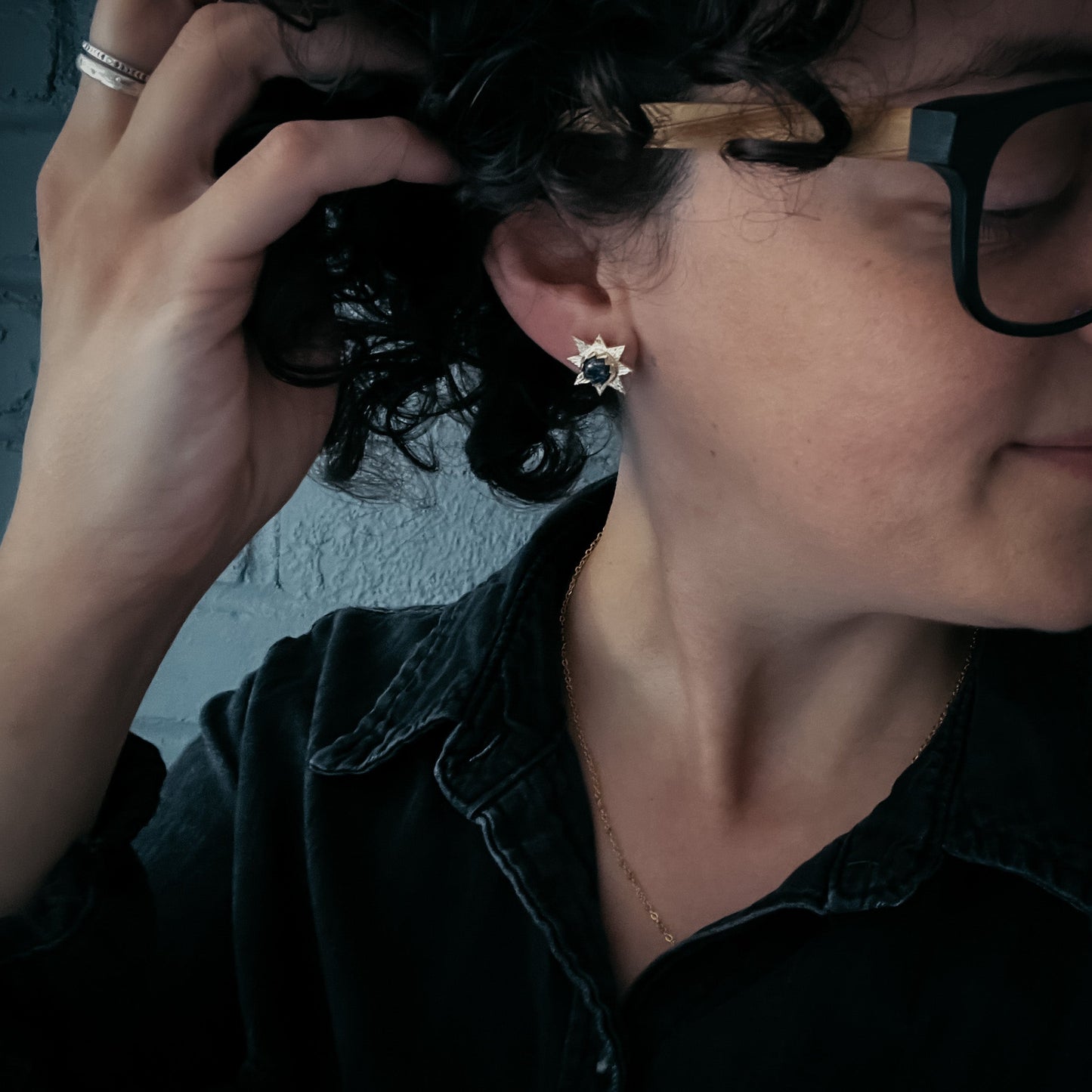 Person adjusting hair with a star-shaped earring visible