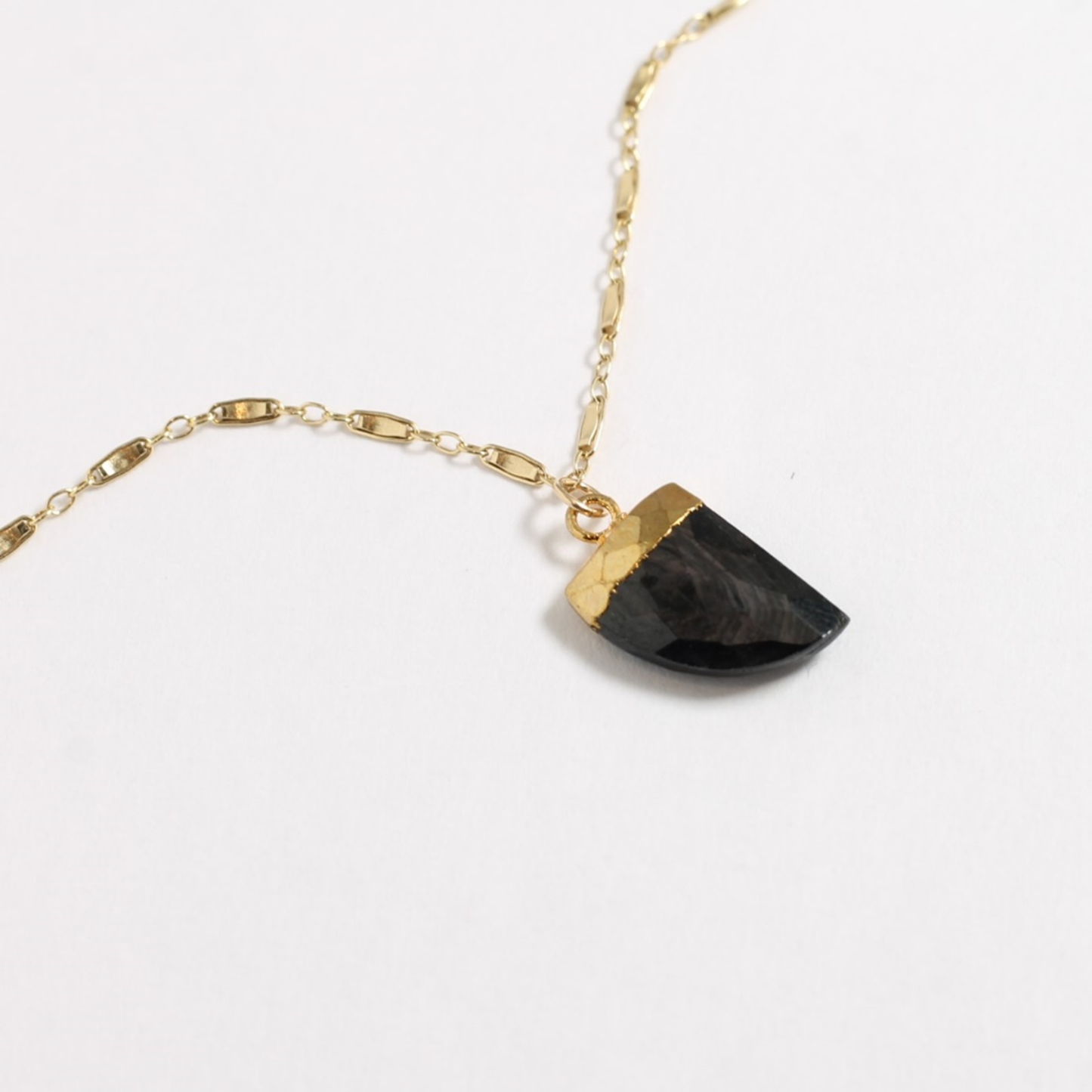Necklace with black stone pendant and gold accents on a white background