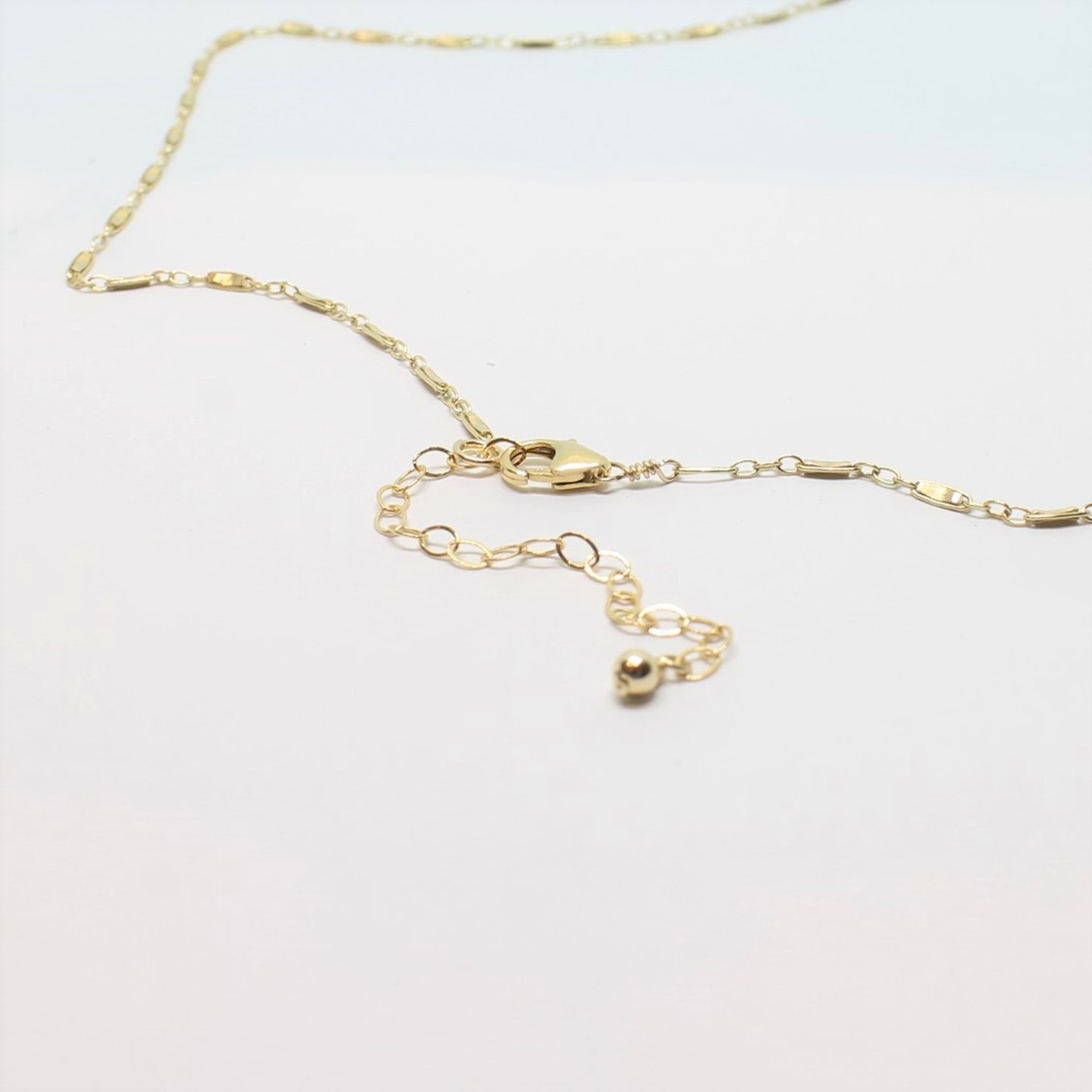 Gold necklace with a heart pendant on a light gray background