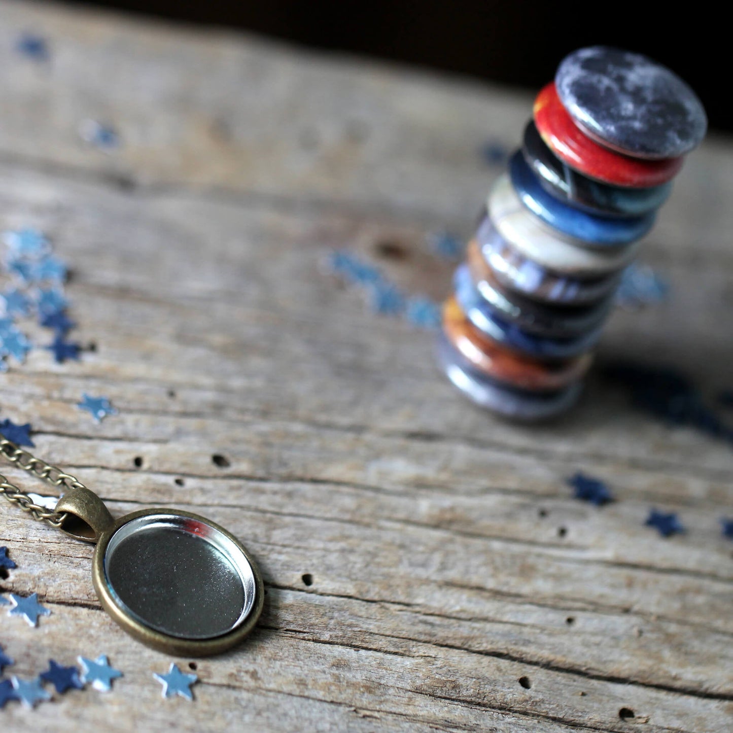 Stack of colorful circular objects and a necklace with a round pendant on a wooden surface.