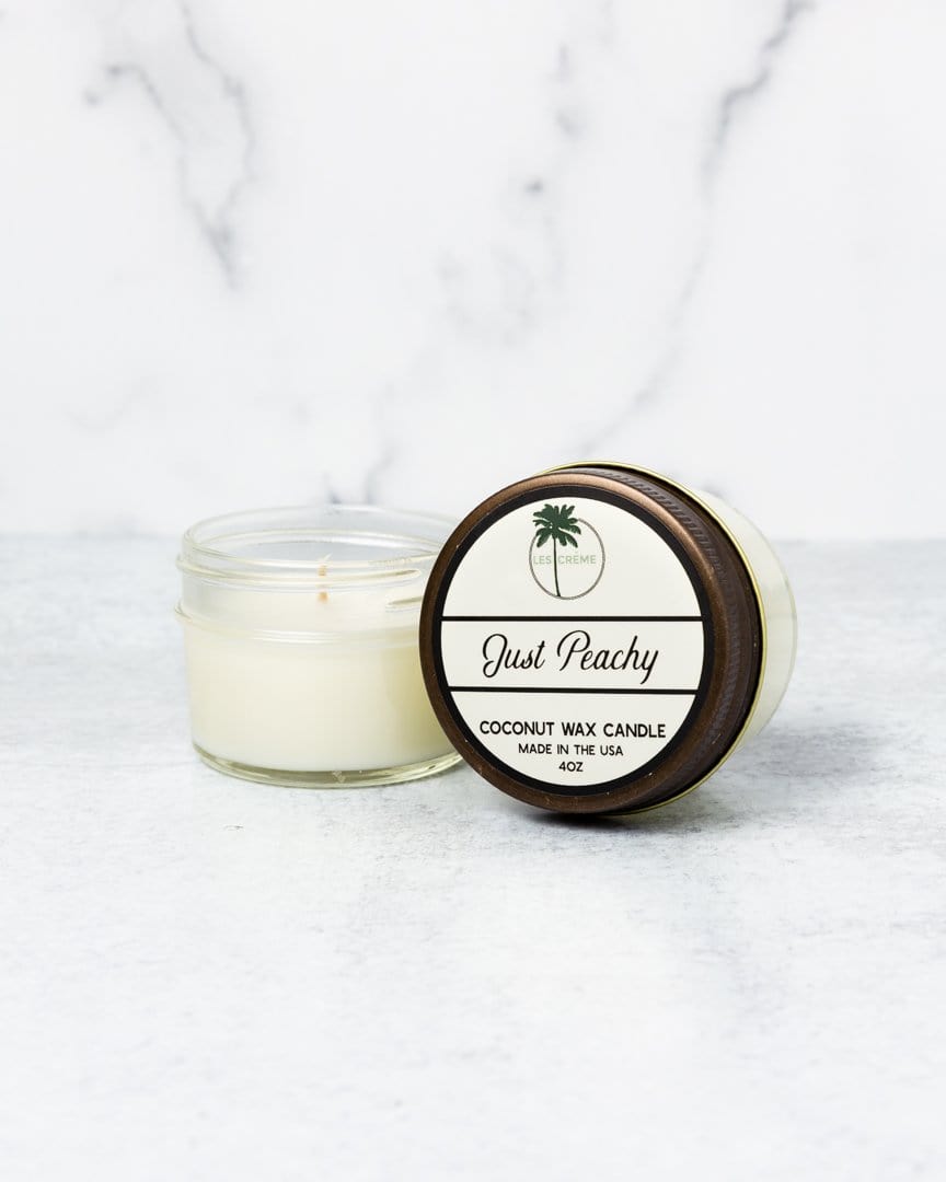Coconut wax candle labeled 'Just Peachy' on a marble surface