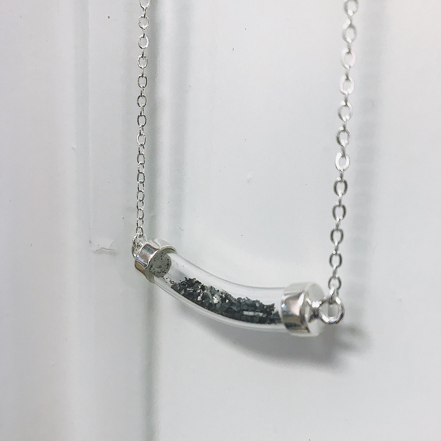 Silver necklace with a curved pendant on a white background