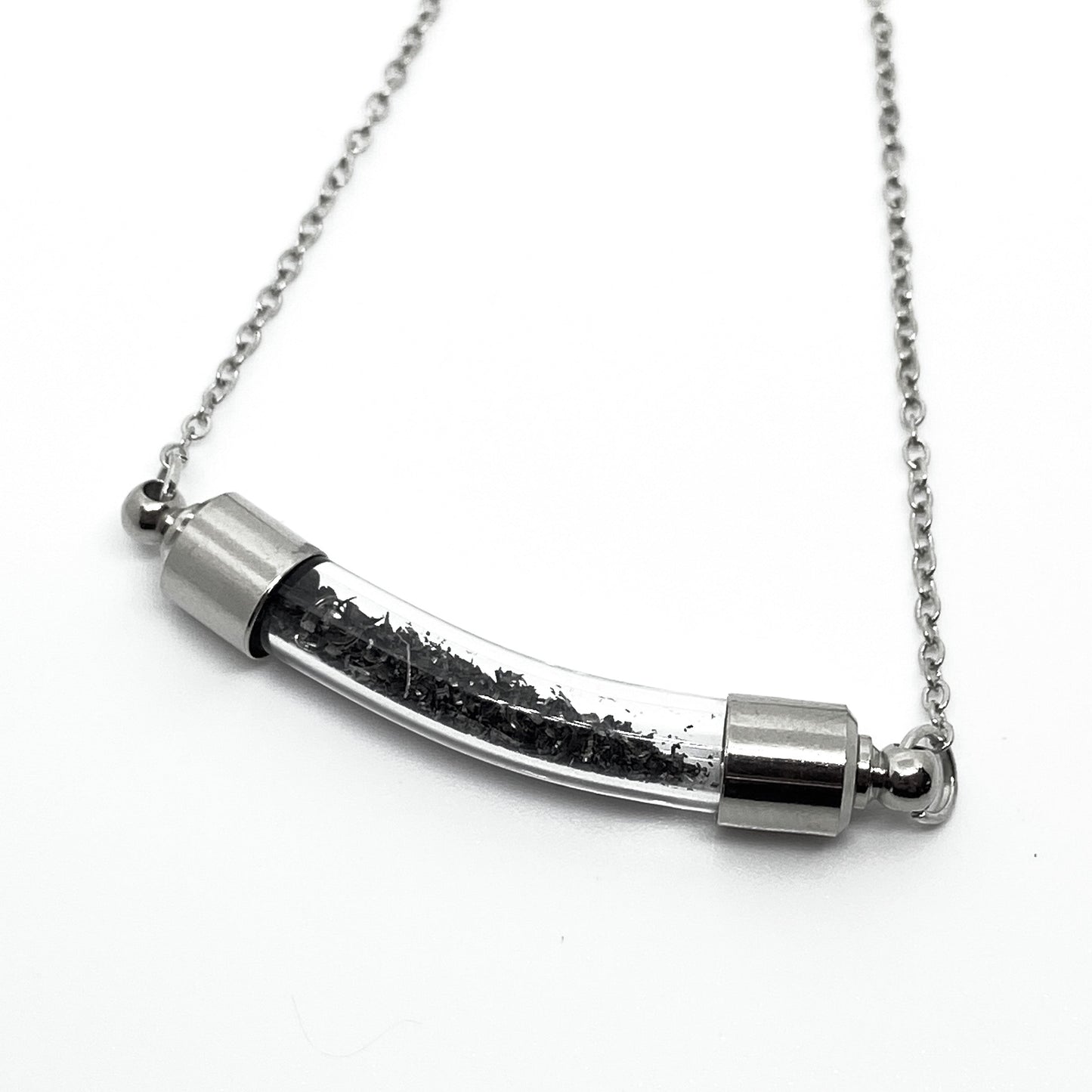 Silver necklace with a cylindrical pendant on a white background
