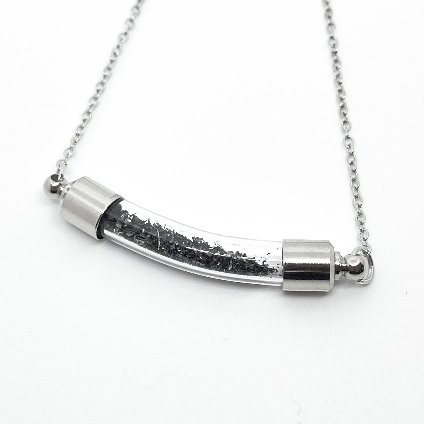 Silver necklace with a cylindrical pendant on a white background