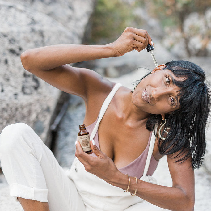 Woman applying a dropper of a skincare product outdoors