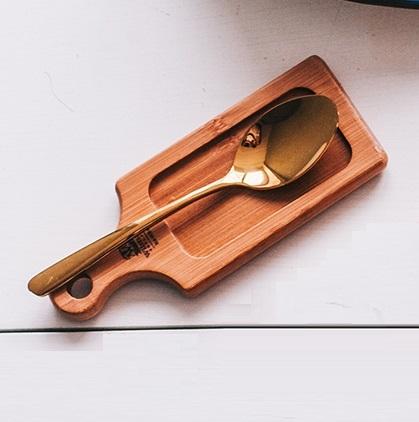 Wooden cutting board with a gold spoon on a white surface