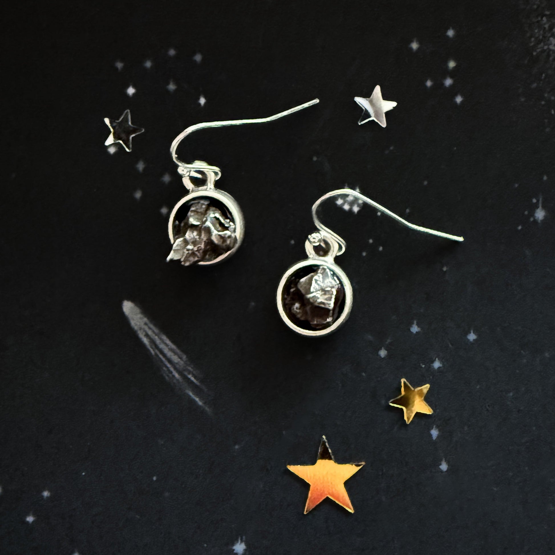 Silver earrings with gemstones on a dark background with star decorations