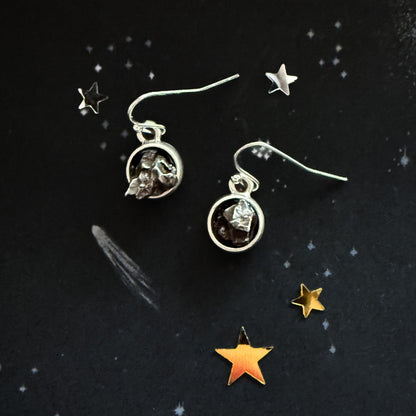Silver earrings with gemstones on a dark background with star decorations