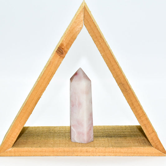 Pink crystal on a wooden triangle stand against a white background