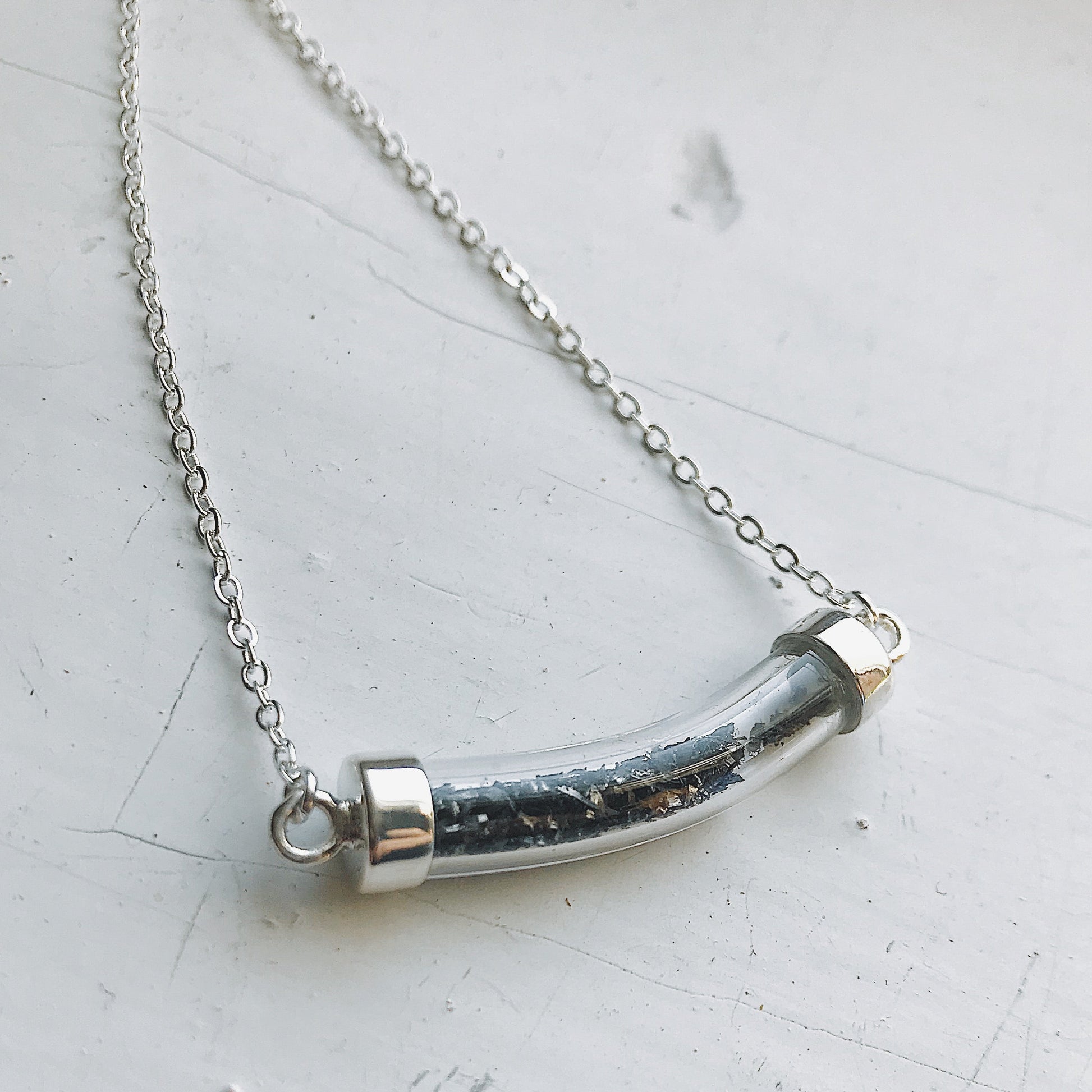 Necklace with a cylindrical pendant on a light gray background