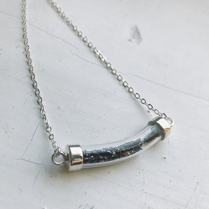 Necklace with a cylindrical pendant on a light gray background