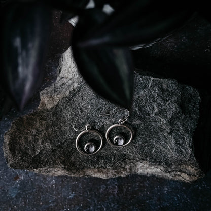 Silver earrings on a dark stone surface
