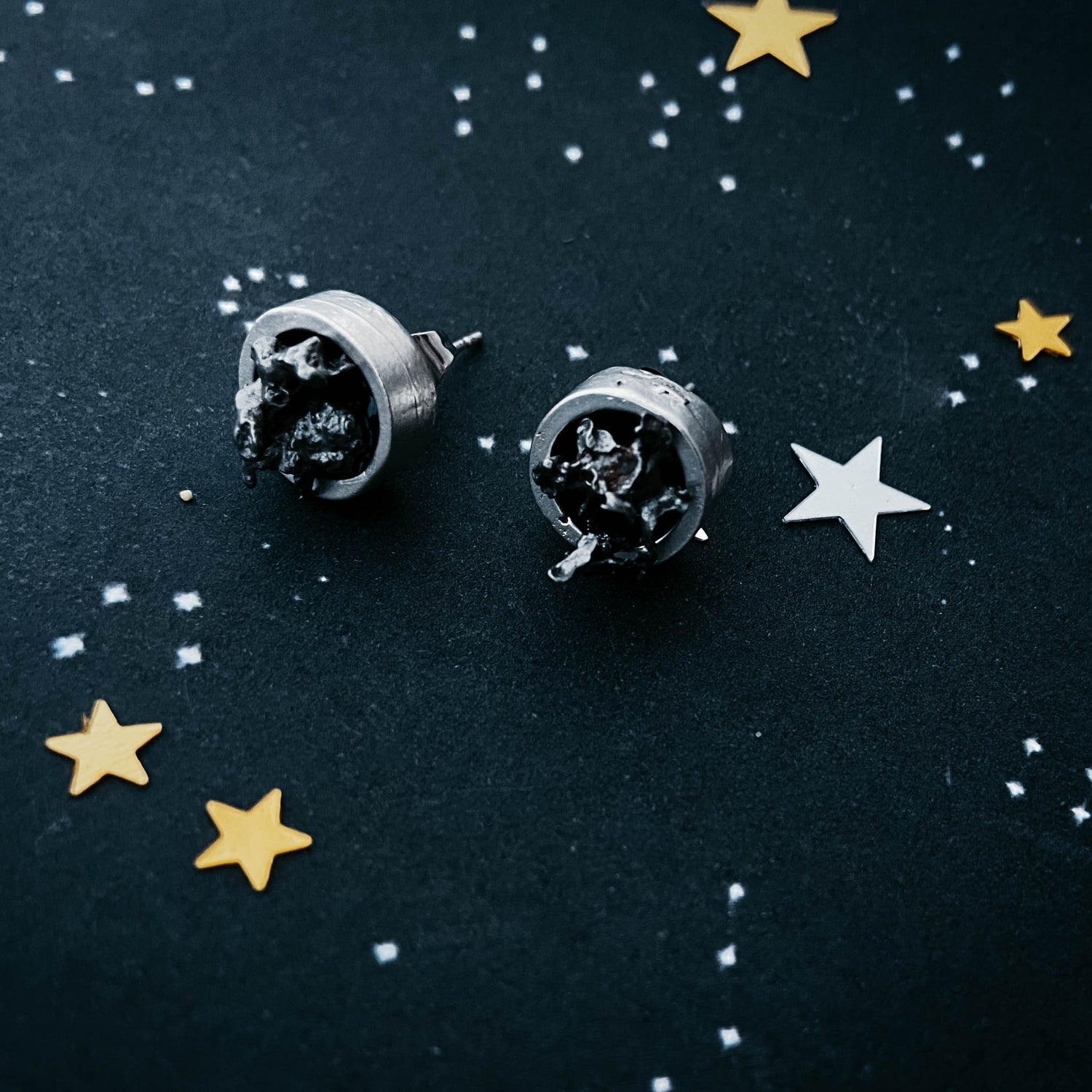 Pair of silver earrings on a dark background with star decorations