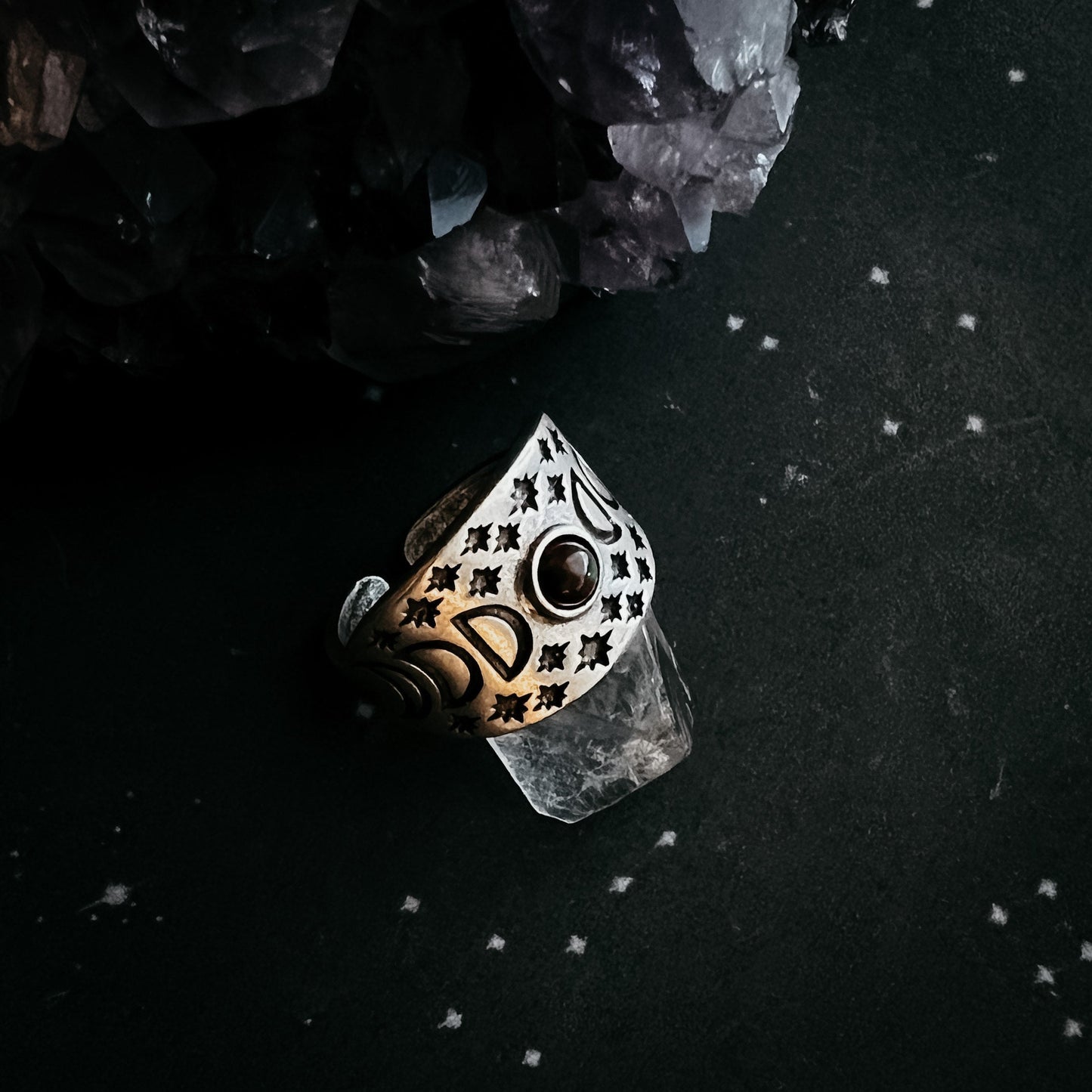 Decorative ring with intricate design on a dark surface with crystals