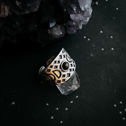 Decorative ring with intricate design on a dark surface with crystals