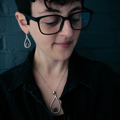 Person wearing black glasses and a black shirt with a dark background