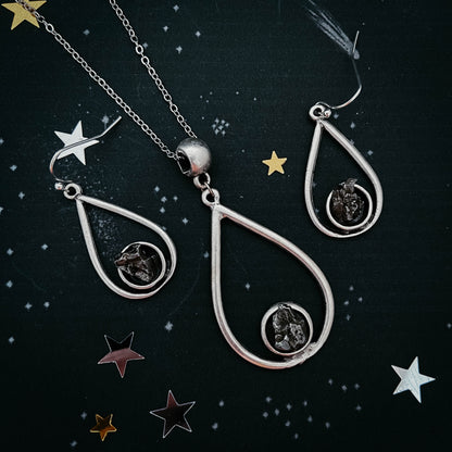 Silver teardrop-shaped jewelry set with star decorations on a dark background