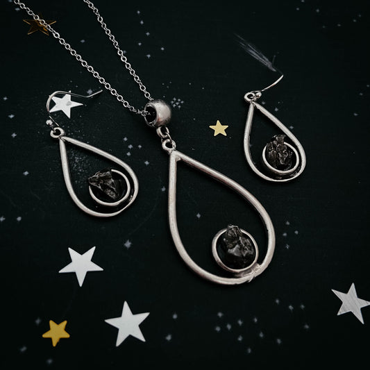 Silver teardrop-shaped jewelry set with star decorations on a dark background