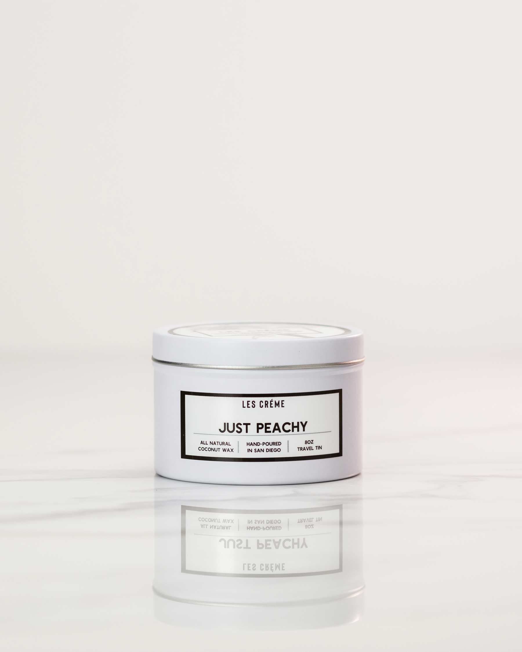 White candle jar labeled 'Just Peachy' by Les Creme on a white background