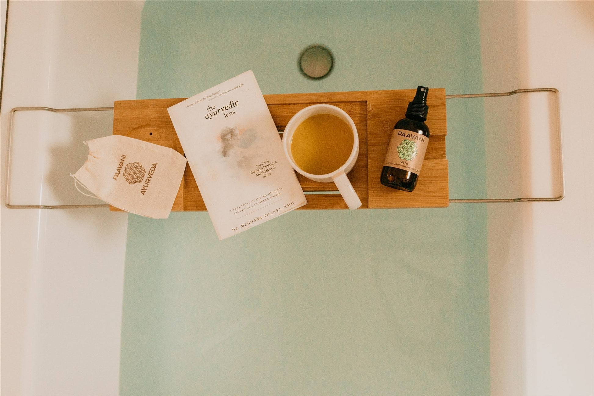 Bath caddy with cup, book, and bottle on a bathtub ledge