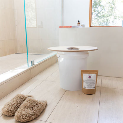White cylindrical product on a bathroom floor with slippers and a package nearby.