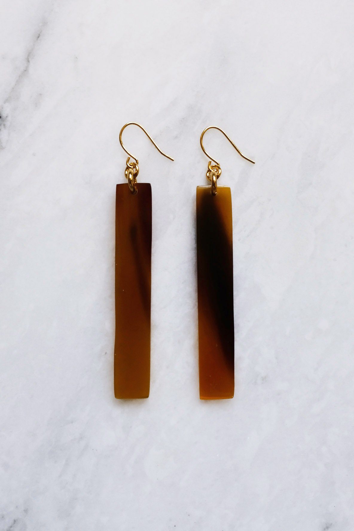 Pair of brown bar earrings on a marble surface