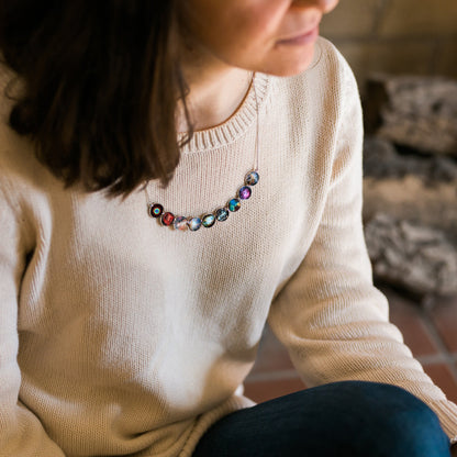 Person wearing a colorful beaded necklace with a neutral background