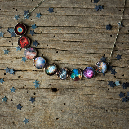 Necklace with colorful galaxy pendants on a wooden surface with star decorations