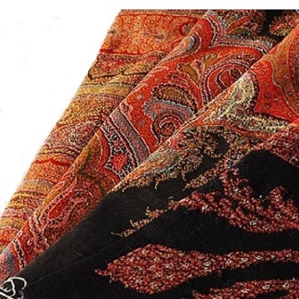 Close-up of a patterned fabric with intricate designs in red, black, and gold.