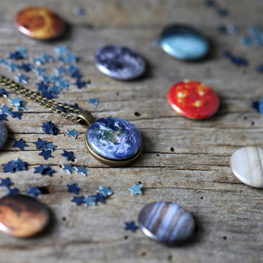 Necklace with space-themed pendant on a wooden surface with star-shaped confetti