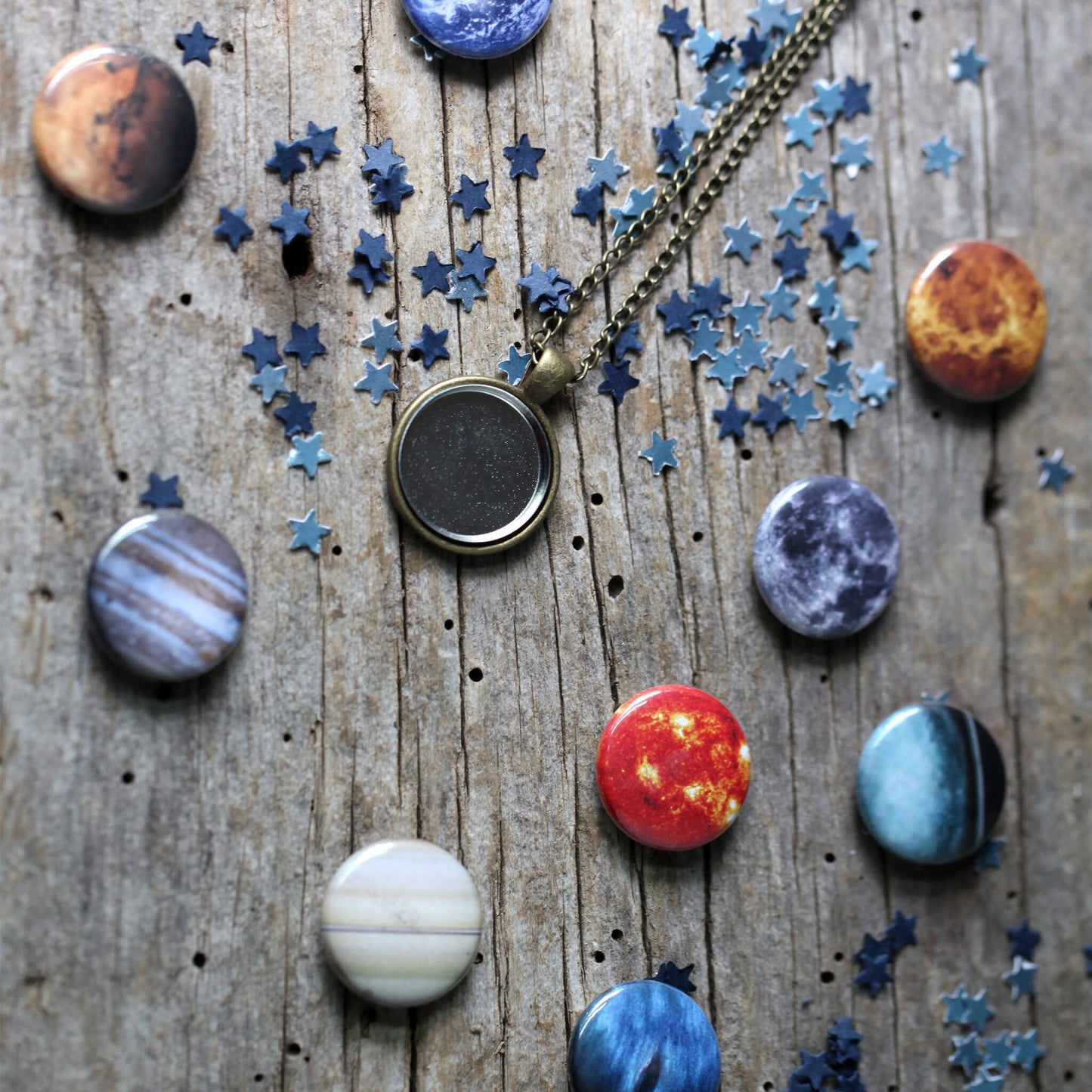 Necklace with pendant surrounded by planet and star-shaped pendants on a wooden surface