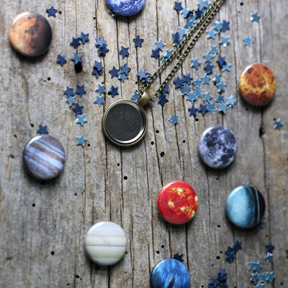 Necklace with pendant surrounded by planet and star-shaped pendants on a wooden surface