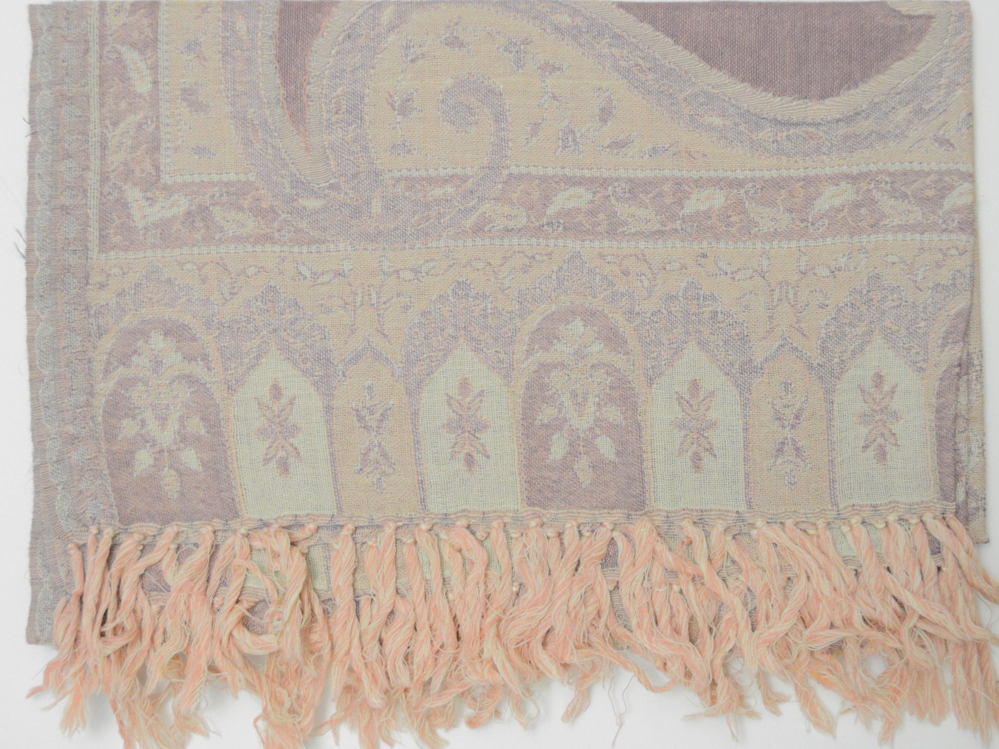 Textile with intricate patterns and fringes on a plain background