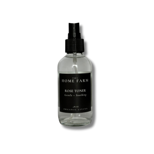 Clear glass bottle with black spray nozzle labeled 'The Home Farm Rose Toner' on a white background
