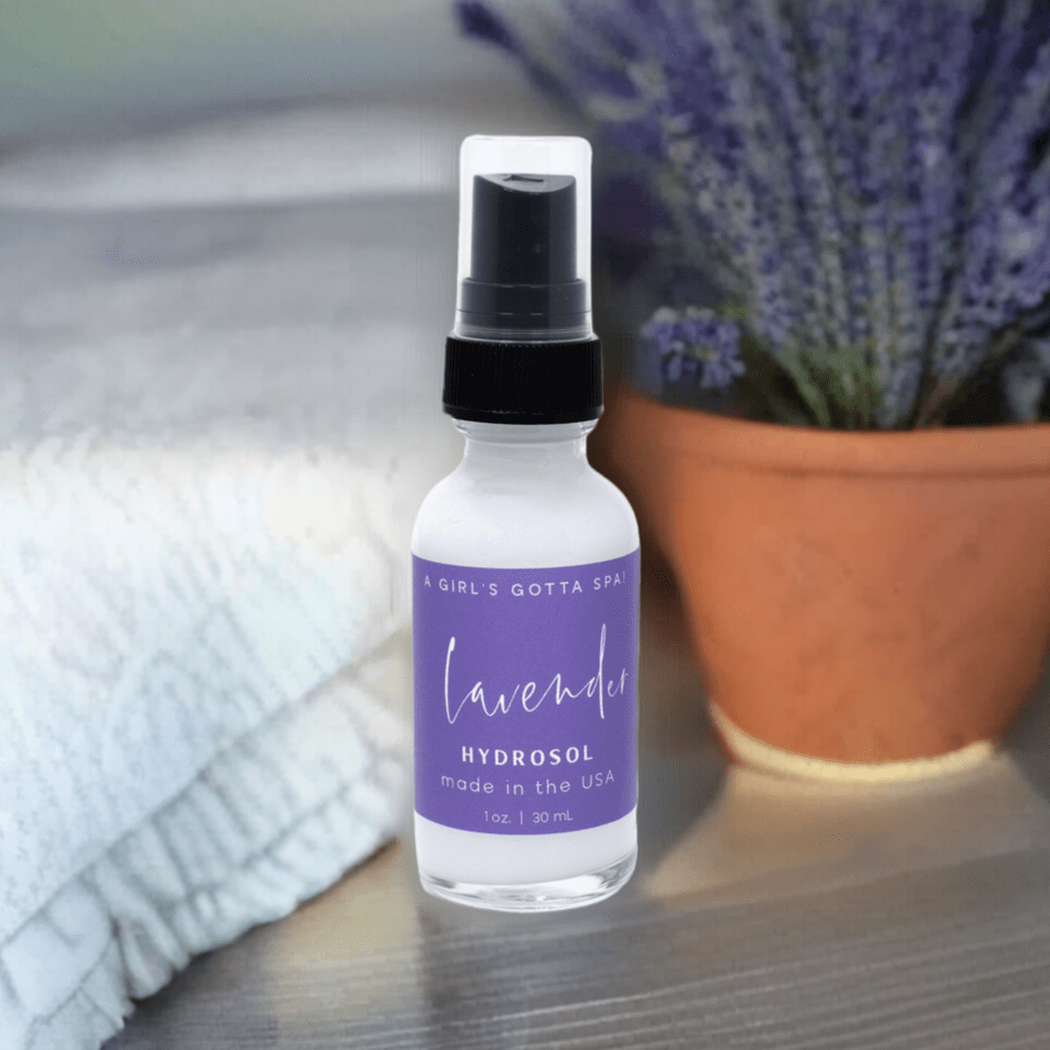 Bottle of lavender hydrosol with a plant and towel in the background
