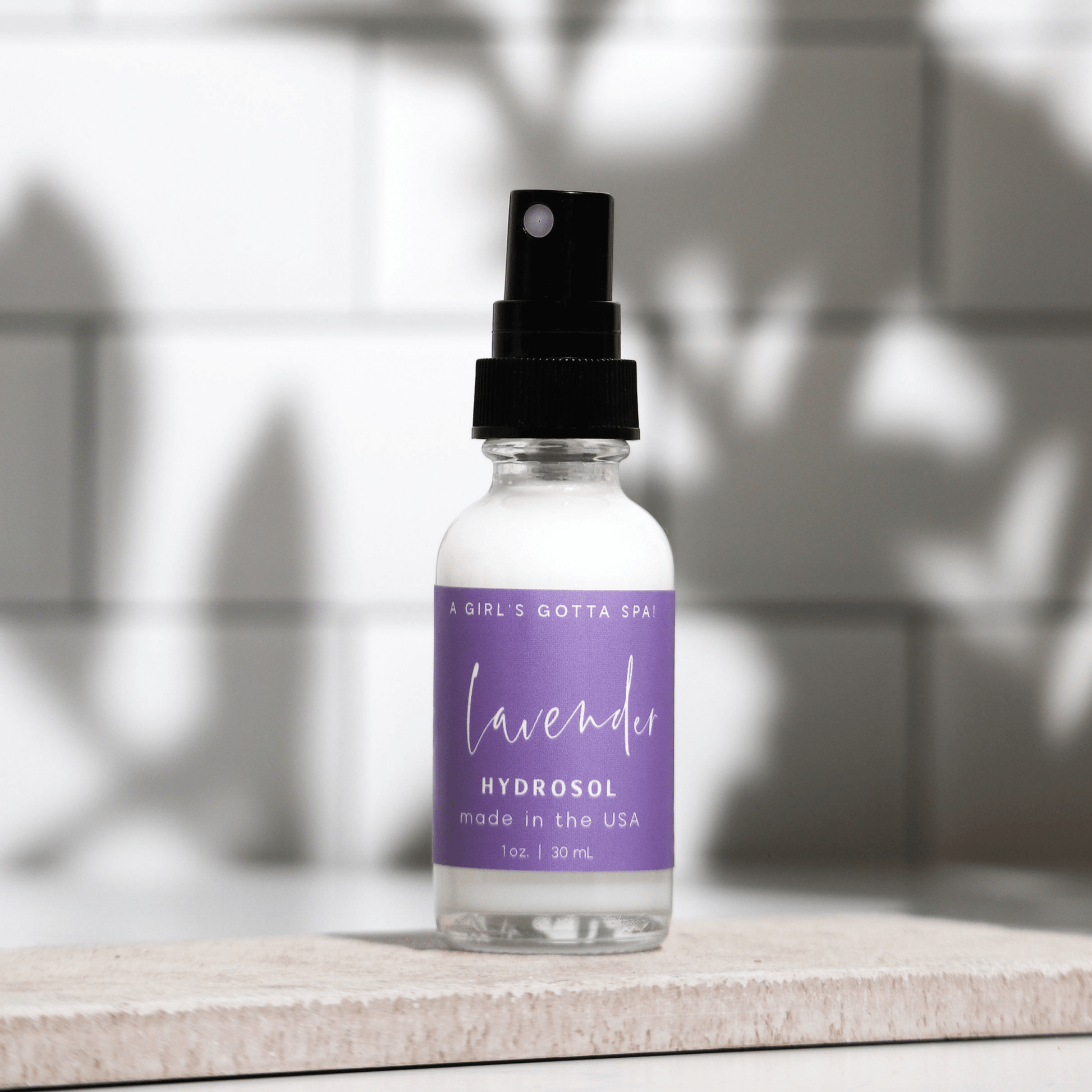 Bottle of lavender hydrosol with a purple label on a neutral background