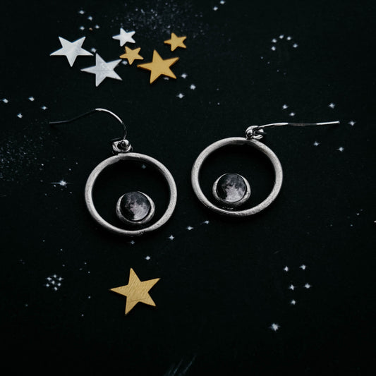 Earrings with celestial design on a starry background