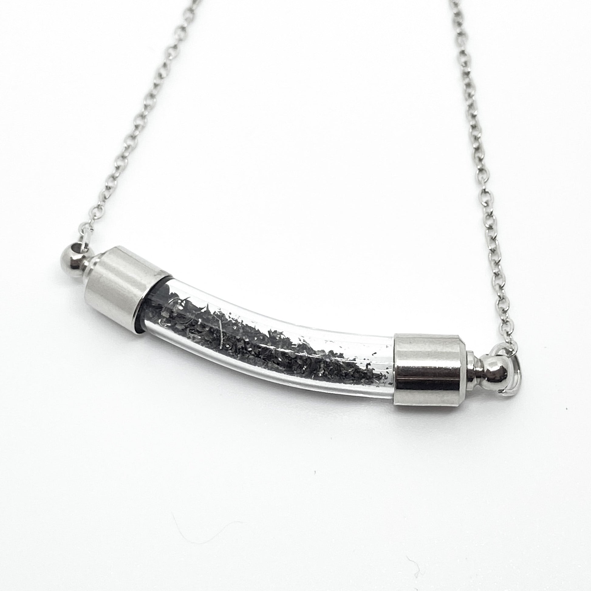 Silver necklace with a cylindrical pendant on a white background