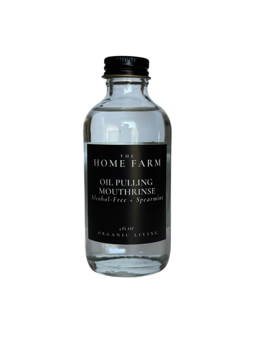 Clear bottle of oil pulling mouthrinse with black label on a white background